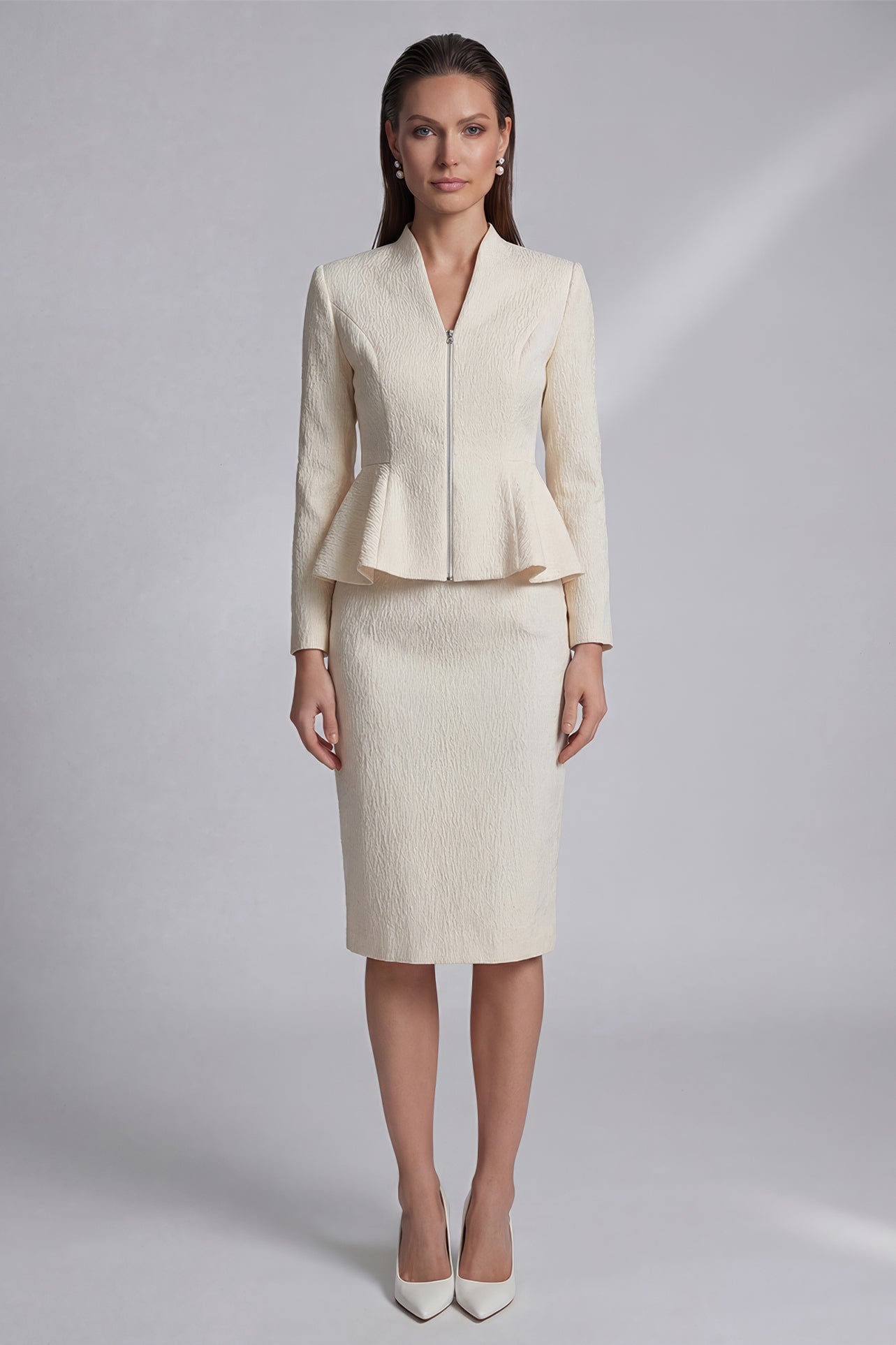 A professional woman wearing a sophisticated cream tweed skirt suit, featuring a tailored jacket with a modern front zipper and an elegant stand collar for a polished executive office look.