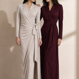 A style comparison of two elegant women's long-sleeve V-neck wrap maxi dresses featuring a flattering side-tie waist and cascading draped ruching; shown on the left in soft oatmeal greige and on the right in rich burgundy wine.