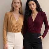 A style comparison of two elegant long-sleeve V-neck wrap tops featuring delicate shoulder pleating and a sleek tucked-in fit; the left in warm camel paired with cream trousers, and the right in deep burgundy paired with black trousers.
