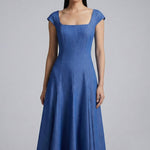 A professional woman modeling an elegant mid-blue midi dress featuring a structured square neckline, delicate cap sleeves, and a flattering high-waisted A-line flare skirt for a sophisticated summer look.