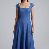 A professional woman modeling an elegant mid-blue midi dress featuring a structured square neckline, delicate cap sleeves, and a flattering high-waisted A-line flare skirt for a sophisticated summer look.