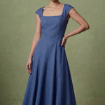 A professional woman modeling an elegant mid-blue midi dress featuring a classic square neckline, cap sleeves, and a flattering A-line flare skirt, perfect for both business and social occasions.