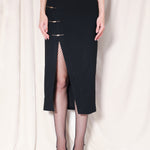 A professional woman wearing a sophisticated high-waisted black pencil skirt, featuring elegant gold-tone mandarin-style buttons and a stylish side slit for a polished executive office look.