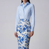 An elegant professional woman wearing a high-waisted pencil skirt featuring a sophisticated blue and white floral porcelain-style print, perfect for a polished office look.
