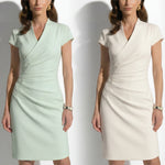 Two professional models wearing elegant sleeveless surplice V-neck sheath dresses in soft mint green and cream ivory, featuring sophisticated side ruched detailing and a tailored slim fit for a polished office look.