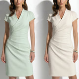 Two professional models wearing elegant sleeveless surplice V-neck sheath dresses in soft mint green and cream ivory, featuring sophisticated side ruched detailing and a tailored slim fit for a polished office look.