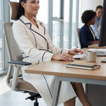 An elegant professional woman wearing a sophisticated white double-breasted coat dress featuring sharp navy blue contrast piping and a matching waist belt for a tailored executive look