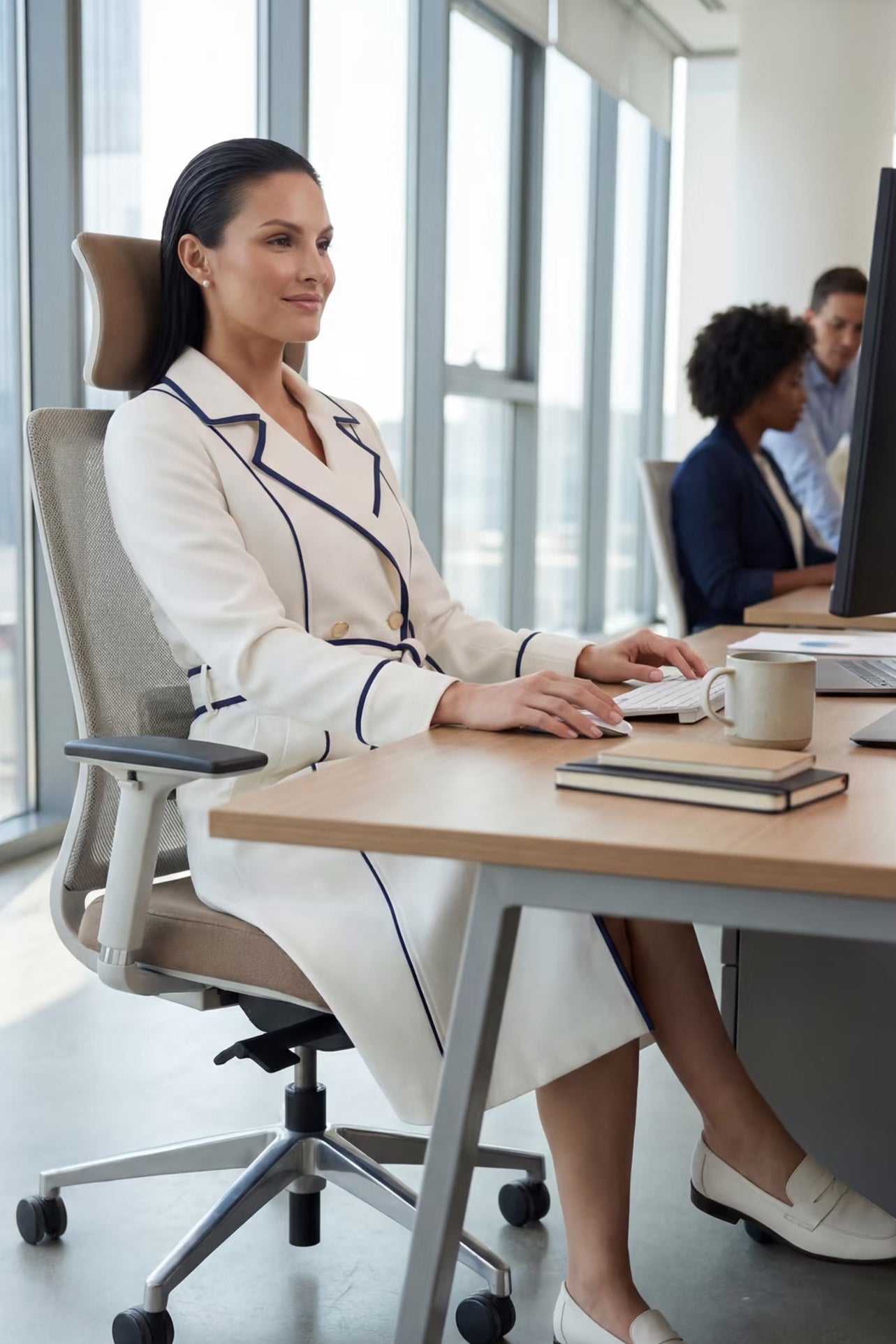 An elegant professional woman wearing a sophisticated white double-breasted coat dress featuring sharp navy blue contrast piping and a matching waist belt for a tailored executive look
