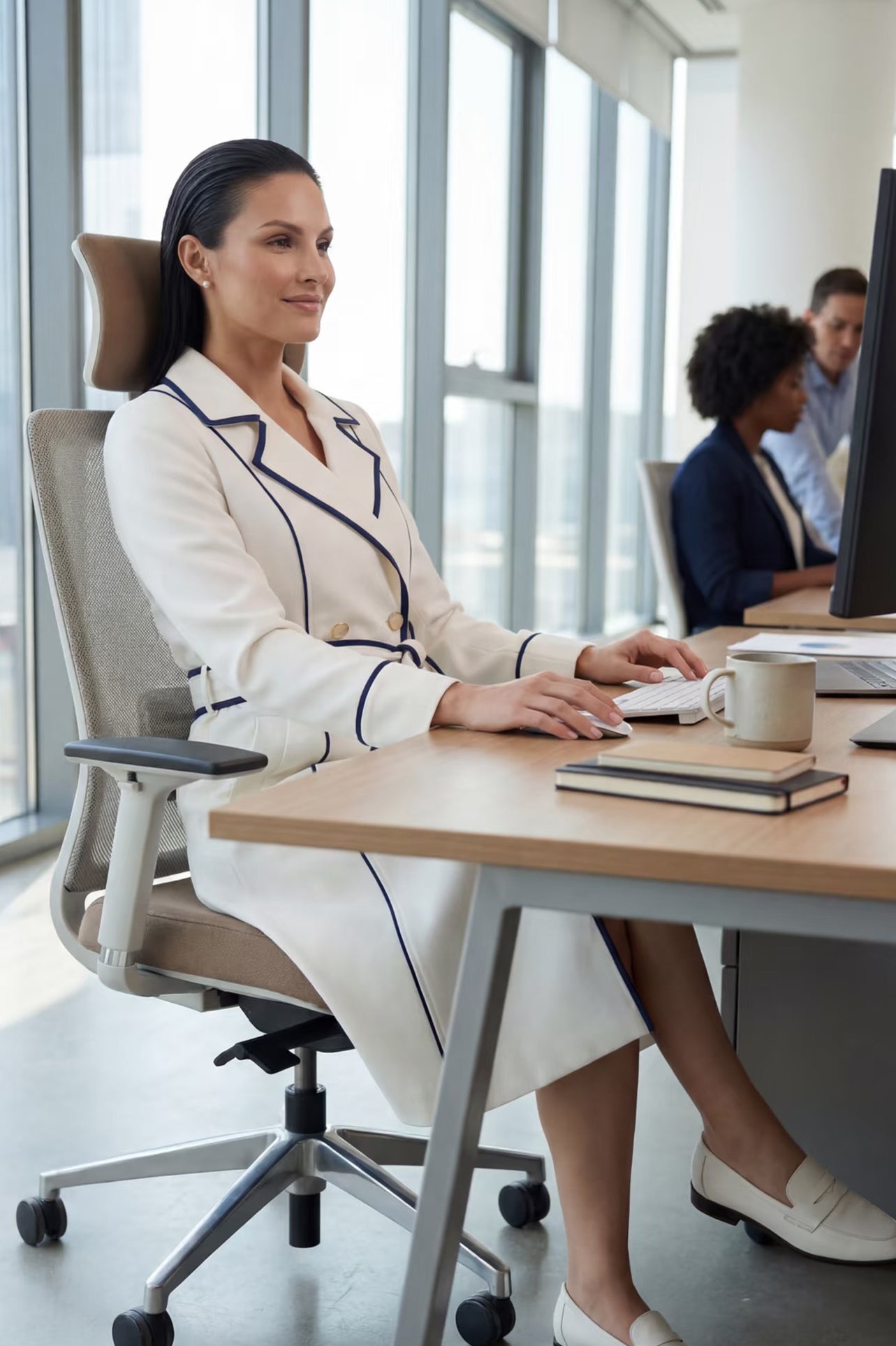An elegant professional woman wearing a sophisticated white double-breasted coat dress featuring sharp navy blue contrast piping and a matching waist belt for a tailored executive look