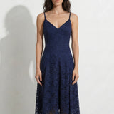 A professional woman modeling an elegant navy blue lace midi dress, featuring delicate V-neck spaghetti straps, a tailored fit-and-flare silhouette, and a beautiful flowing asymmetric handkerchief lace trim hem.