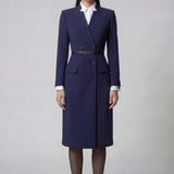 An elegant professional woman wearing a sophisticated navy blue double-breasted long coat dress, featuring a black waist belt and structured shoulders for a powerful executive look.