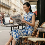 A professional woman wearing a sophisticated modern qipao dress, featuring a blue and white porcelain floral print, a mandarin collar with keyhole detail, and a slimming tailored fit for an elegant executive look.