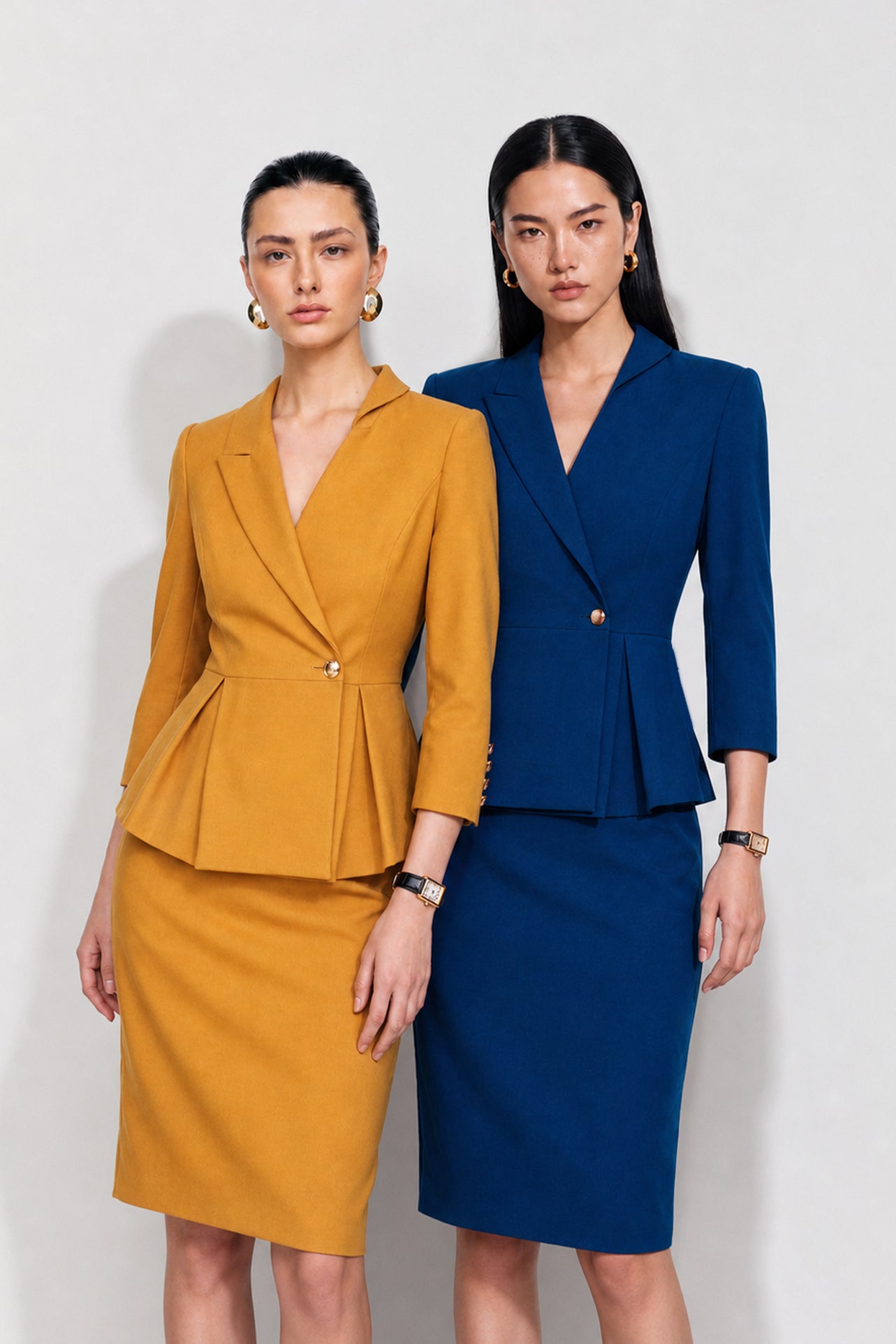 A style comparison of two elegant women's skirt suit sets featuring three-quarter sleeve blazers with single-button closure and pleated peplum hems, paired with matching pencil skirts in mustard yellow and deep teal blue.