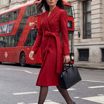 A sophisticated woman walking in London wearing an elegant vibrant red wrap coat dress, featuring a tie-waist belt and notched lapels for a polished executive street style look.