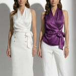 A professional woman modeling elegant satin halter wrap tops in crisp white and deep purple, featuring a sophisticated side bow tie and paired with white high-waisted trousers and a button-front skirt.