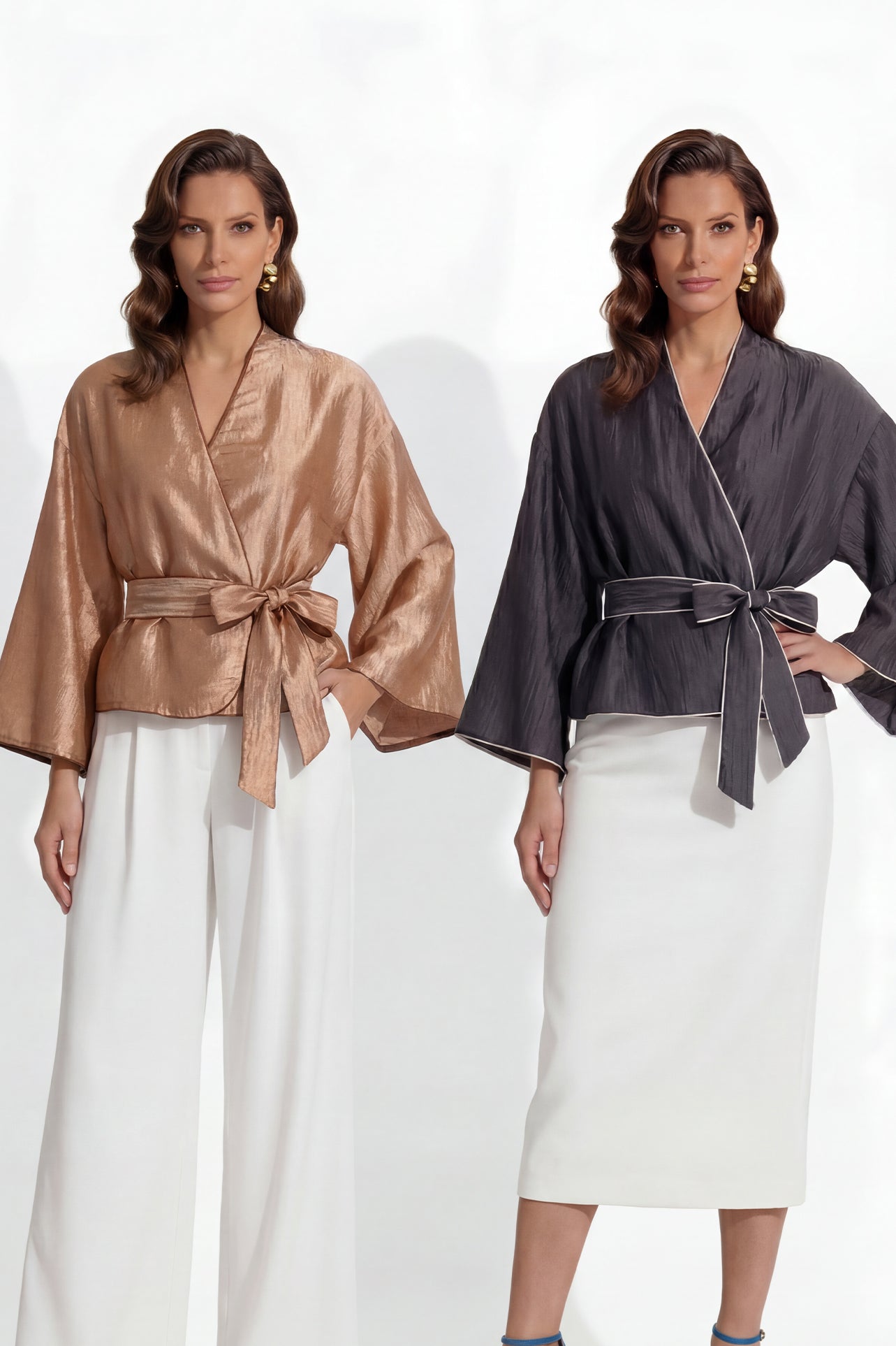 Two professional models wearing elegant shimmering satin wrap tops with kimono-style sleeves and waist ties, one in champagne gold and the other in charcoal grey with contrast white piping, paired with ivory high-waisted trousers.