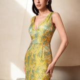 A professional woman wearing a stunning gold and teal jacquard sheath dress, featuring a sophisticated V-neckline and elegant artistic wave patterns for a high-end formal look.