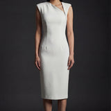 A professional woman wearing a sophisticated ivory sleeveless sheath dress, featuring a unique asymmetric zipper neckline and a tailored slim-fit silhouette for a modern executive office or cocktail look.