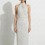 A professional woman modeling an elegant white lace halter neck modern qipao dress, featuring a sophisticated mandarin collar with keyhole detail and an intricate eyelet embroidered fabric for a quiet luxury look.