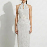 A professional woman modeling an elegant white lace halter neck modern qipao dress, featuring a sophisticated mandarin collar with keyhole detail and an intricate eyelet embroidered fabric for a quiet luxury look.