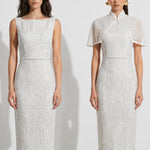 A collection of two professional models wearing elegant white lace midi dresses; the left showcasing a minimalist sleeveless bateau neck sheath dress, and the right featuring a modern Chinese qipao with a sophisticated capelet sleeve detail and traditional mandarin collar.