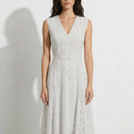 A professional woman modeling an elegant white lace sleeveless dress, featuring a sophisticated V-neckline, a tailored fit-and-flare silhouette, and an intricate hollow-out eyelet texture with a delicate lace trim hem.