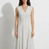 A professional woman modeling an elegant white lace sleeveless dress, featuring a sophisticated V-neckline, a tailored fit-and-flare silhouette, and an intricate hollow-out eyelet texture with a delicate lace trim hem.