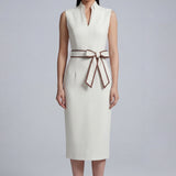 A professional woman modeling an elegant white sleeveless midi dress, featuring a sophisticated stand collar with a V-neck slit and a chic brown contrast bow belt for a polished office look.