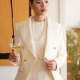 A professional woman wearing a sophisticated cream white double-breasted tweed blazer, featuring elegant gold buttons, a tailored slim fit, and classic flap pockets for a polished executive look.