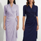 Two professional models wearing elegant wrap midi dresses with elbow-length sleeves; the left in a soft pastel lavender and the right in a deep navy blue, both featuring a sophisticated surplice V-neckline and slimming side ruched draping with a waist tie