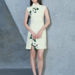 A professional woman wearing a stunning lemon yellow sleeveless mini dress, featuring a traditional mandarin collar, exquisite white floral 3D embroidery, and an elegant side slit for a sophisticated modern oriental look.