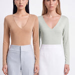 A style comparison of two elegant women's long-sleeve deep V-neck tops featuring subtle rhinestone crystal embellishments; shown on the left in nude camel tucked into tailored trousers, and on the right in pale mint green styled with a white skirt.