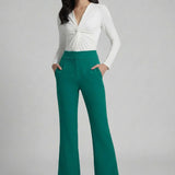 A professional woman wearing sophisticated emerald green high-waisted flare trousers, featuring a tailored slim fit through the hip and a stylish bootcut silhouette for an elegant office look.