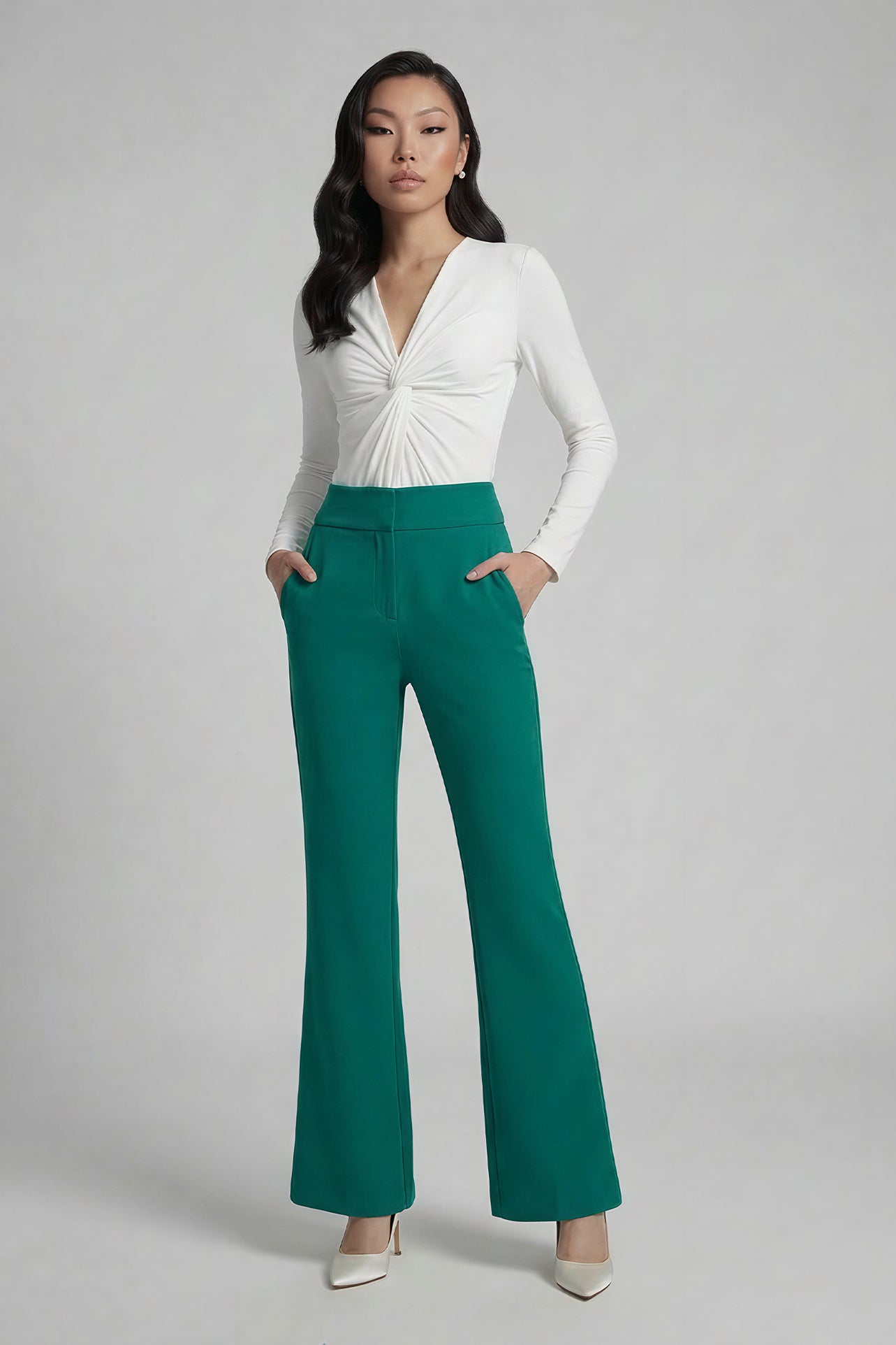 A professional woman wearing sophisticated emerald green high-waisted flare trousers, featuring a tailored slim fit through the hip and a stylish bootcut silhouette for an elegant office look.
