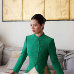 A professional woman wearing a stunning vibrant green blazer, featuring a traditional mandarin collar and elegant frog button detailing for a modern oriental-inspired executive look.