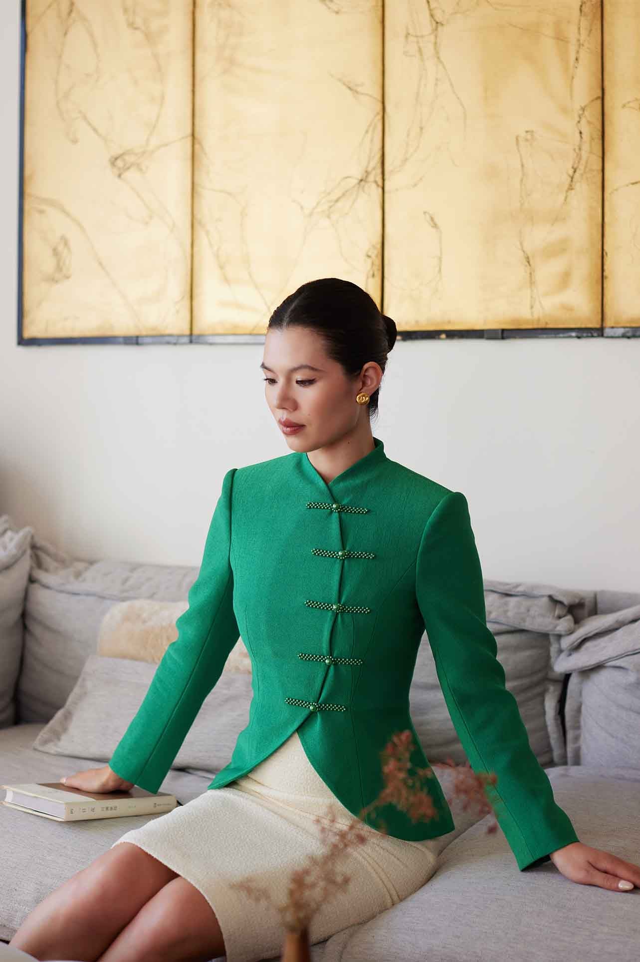A professional woman wearing a stunning vibrant green blazer, featuring a traditional mandarin collar and elegant frog button detailing for a modern oriental-inspired executive look.