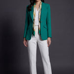 A professional woman wearing a sophisticated emerald green tailored blazer, featuring a slim-fit silhouette, notched lapels, and flap pockets, styled elegantly with a patterned silk scarf for a corporate office look.