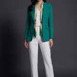 A professional woman wearing a sophisticated emerald green tailored blazer, featuring a slim-fit silhouette, notched lapels, and flap pockets, styled elegantly with a patterned silk scarf for a corporate office look.