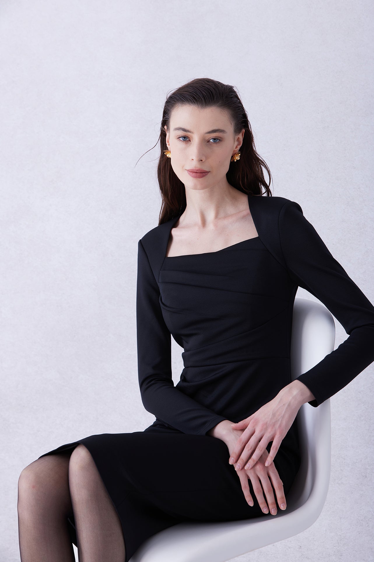 A professional woman wearing a sophisticated deep magenta long-sleeve pencil dress, featuring a unique square neckline and elegant ruched detailing at the waist for a flattering, slim-fit executive look.