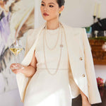 A professional woman wearing a sophisticated cream white double-breasted tweed blazer, featuring elegant gold buttons, a tailored slim fit, and classic flap pockets for a polished executive look.