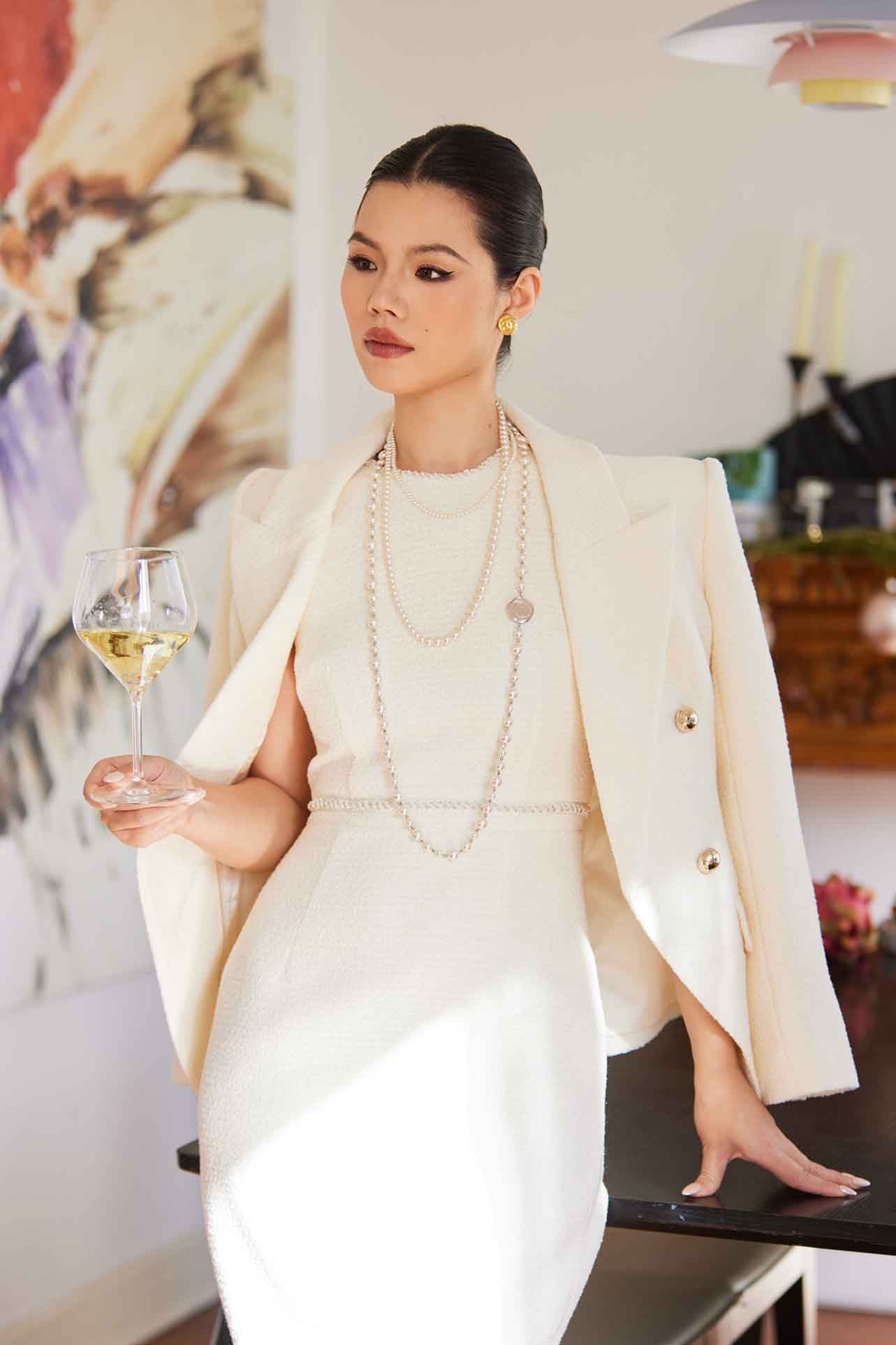 A professional woman wearing a sophisticated cream white double-breasted tweed blazer, featuring elegant gold buttons, a tailored slim fit, and classic flap pockets for a polished executive look.