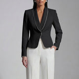 Two elegant professional women modeling high-end monochrome executive suits, one in a black blazer with white piping and wide-leg trousers, the other in a white blazer with dark trim and a matching pencil skirt.