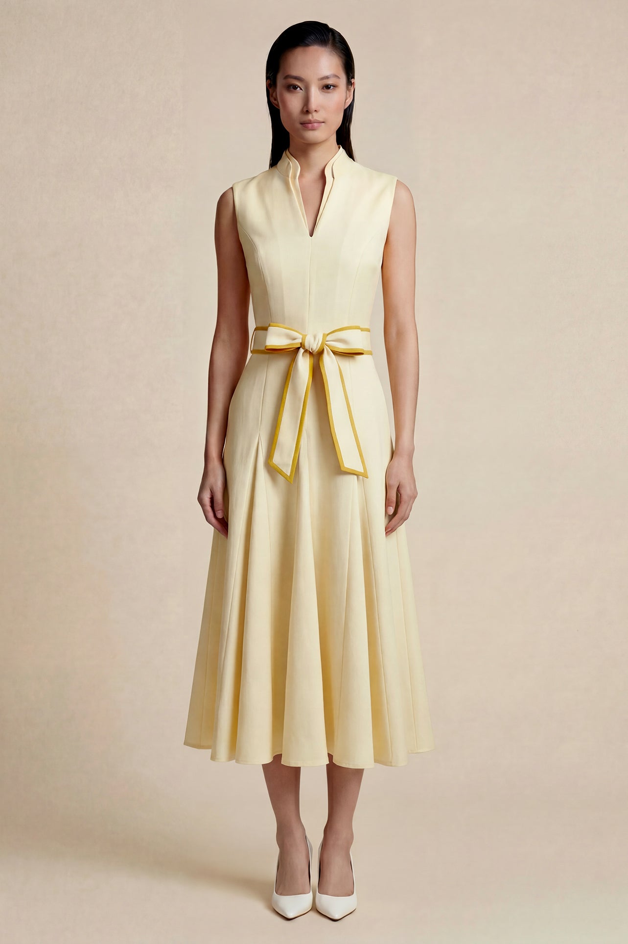 A side-by-side comparison of an elegant pale yellow sleeveless dress in two lengths, featuring a sophisticated mandarin collar, a stylish bow tie-waist, and a pleated A-line skirt for a classic feminine look
