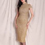 A professional woman wearing a stunning luxurious gold sequined modern qipao dress, featuring a traditional mandarin collar, short cap sleeves, and a slim-fit floor-length silhouette for a formal evening gala.