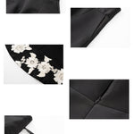 An elegant woman wearing a sophisticated black A-line midi dress, featuring exquisite white floral embroidery along the hem and professional three-quarter sleeves for a timeless formal look.