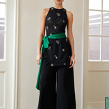 A professional woman wearing sophisticated black high-waisted wide-leg trousers, featuring a flattering high-rise fit and a flowing full-length silhouette for an elegant office look.