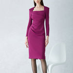 A professional woman wearing a sophisticated deep magenta long-sleeve pencil dress, featuring a unique square neckline and elegant ruched detailing at the waist for a flattering, slim-fit executive look.