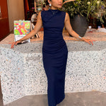 A professional woman wearing a sophisticated navy blue sleeveless midi dress, featuring an elegant high neckline and flattering ruched detailing along the side for a slim-fit executive look.