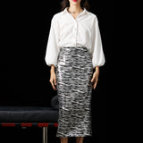 A woman wearing a glamorous high-waisted pencil skirt featuring shimmering silver and black sequins in a stylish zebra print, ideal for an elegant evening party or a night out.