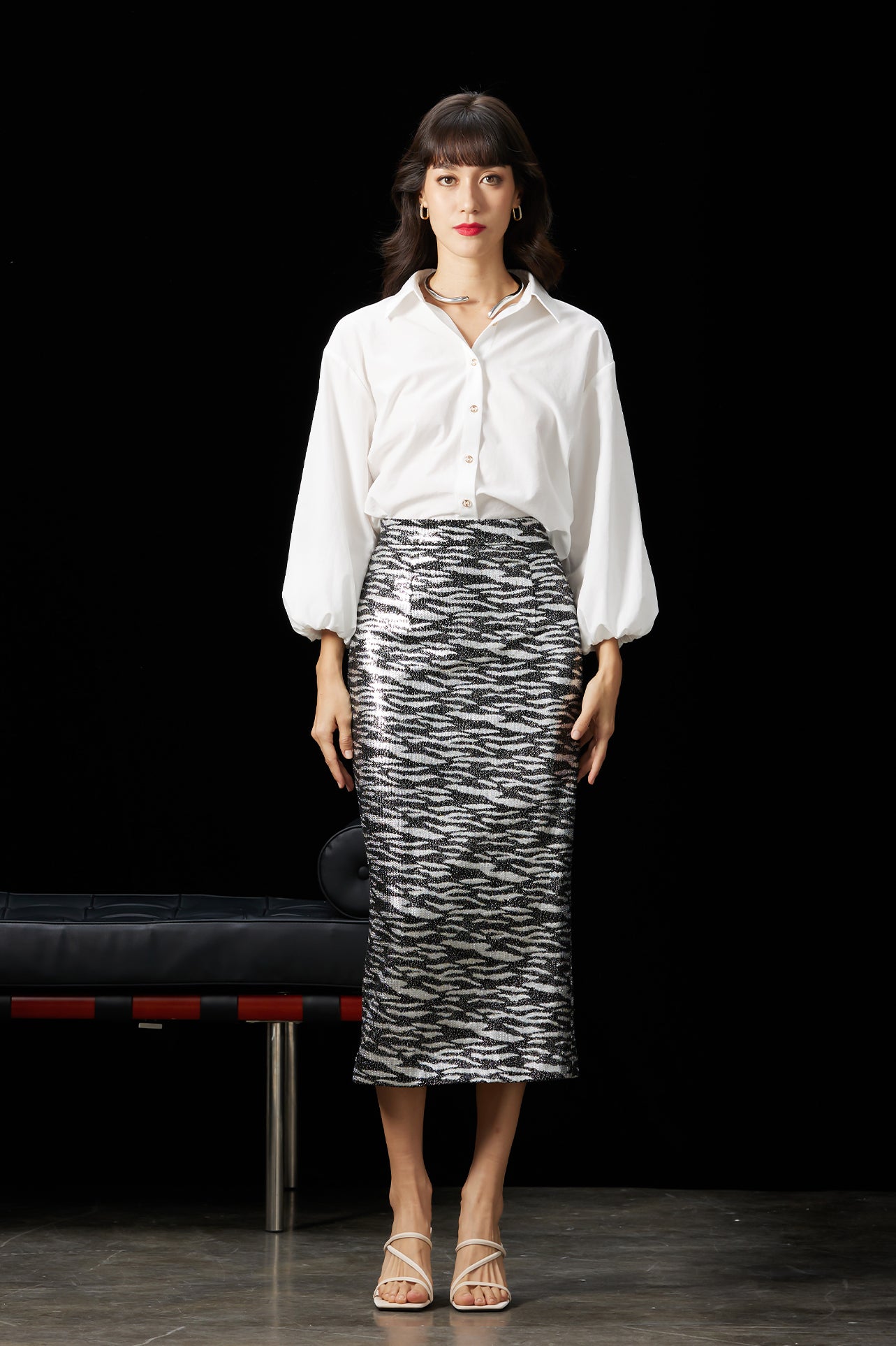 A woman wearing a glamorous high-waisted pencil skirt featuring shimmering silver and black sequins in a stylish zebra print, ideal for an elegant evening party or a night out.
